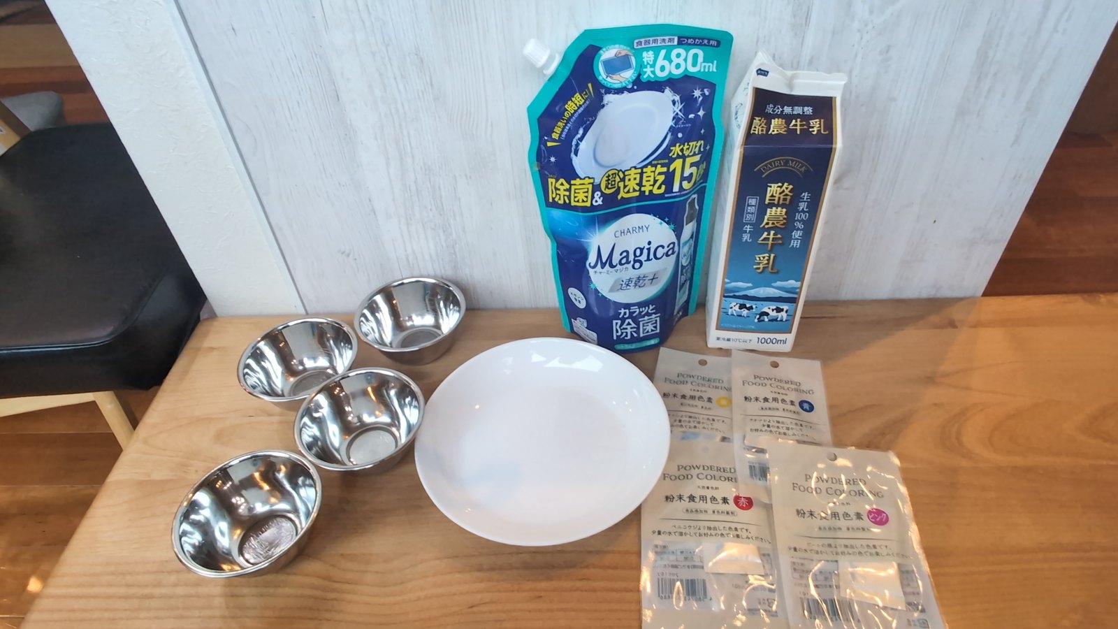白いお皿・牛乳・食器用洗剤・ステンレスの小皿4つ・粉末食用色素4袋をテーブルに並べた写真