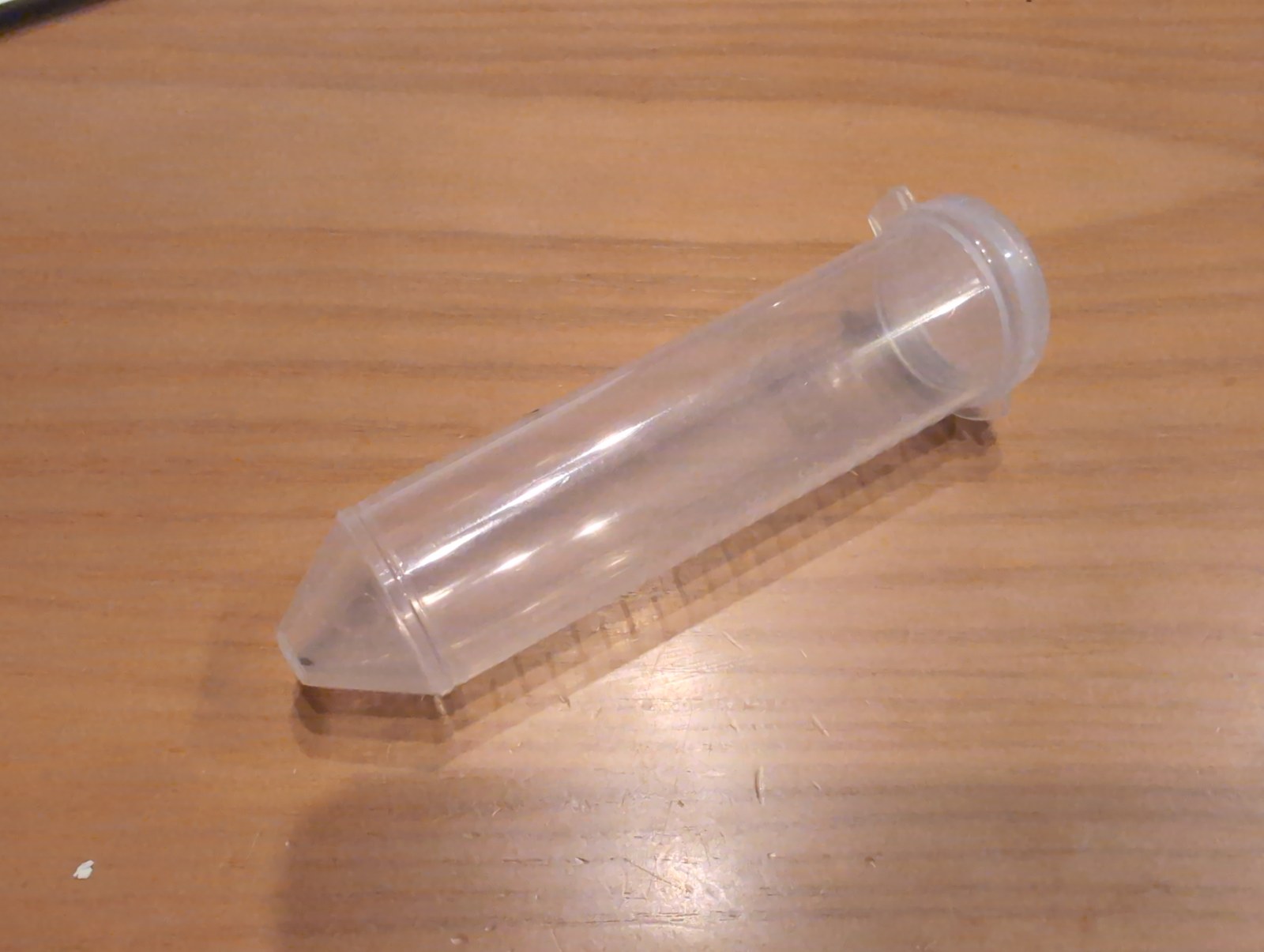 透明なプラスチックの遠沈管が木のテーブルに置かれている
