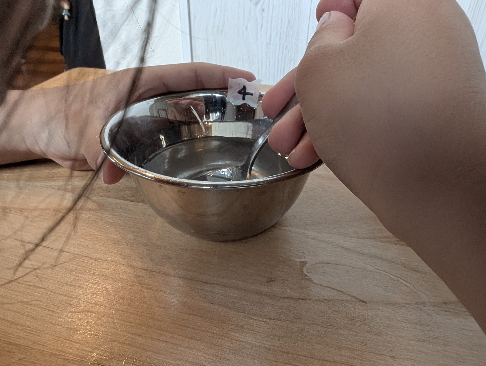 スプーンで器の中の砂糖水をかき混ぜているところ