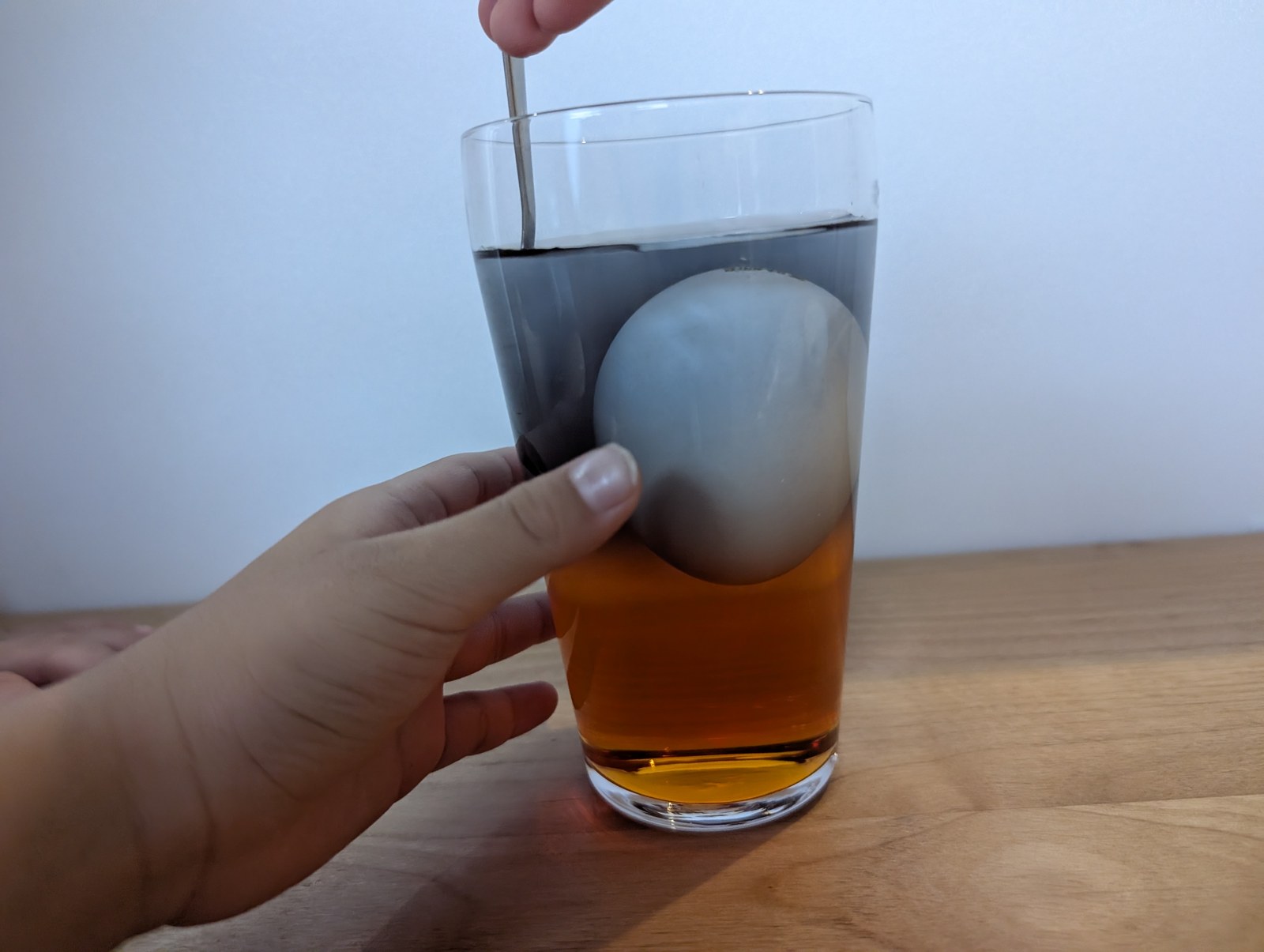 スプーンでグラスの中をかき混ぜているところ。層がくずれ始めている