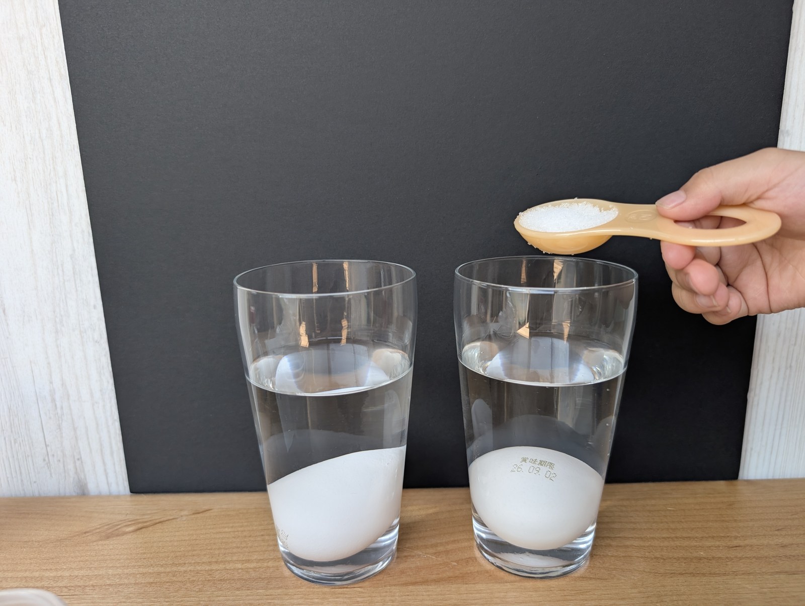 計量スプーンにすくった食塩を、右のコップに入れようとしているところ