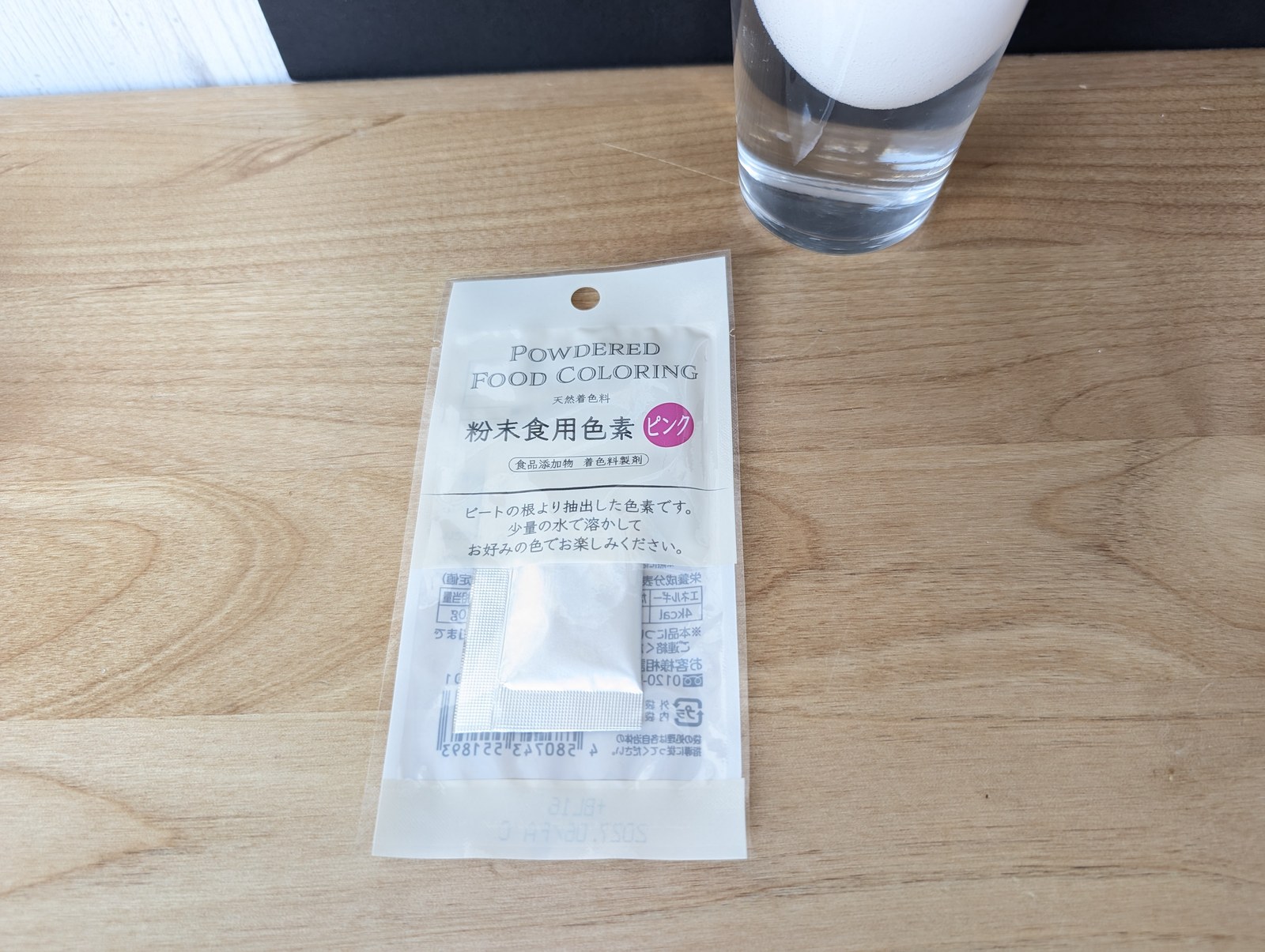 粉末食用色素ピンクの袋と、卵が入ったコップ